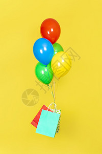 红色的纸袋和一堆气球飞销售礼物交付概念绿色红黄和蓝气球红和蓝纸袋在黄背景上孤立黄色和蓝气球以及在黄色背景上隔离的红色和蓝纸袋惊喜图片