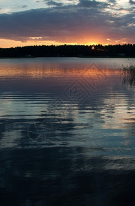 假期在瑞典瓦尔姆兰一个湖与天空反射为宁静水的天空反射在平静水中的和多彩日落在一个湖与天空反光的之间和平多彩日落沉思的经过图片