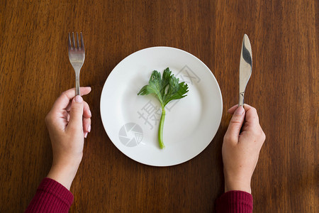 最佳饮食概念空白盘上一种绿色蔬菜女人手放在木桌上芹菜放在木桌上健康顶视图饮食概念芹菜健康极端豌豆图片