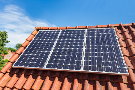 屋顶太阳能电气蓝色的房顶上三个蓝色太阳能收集器的行屋背景