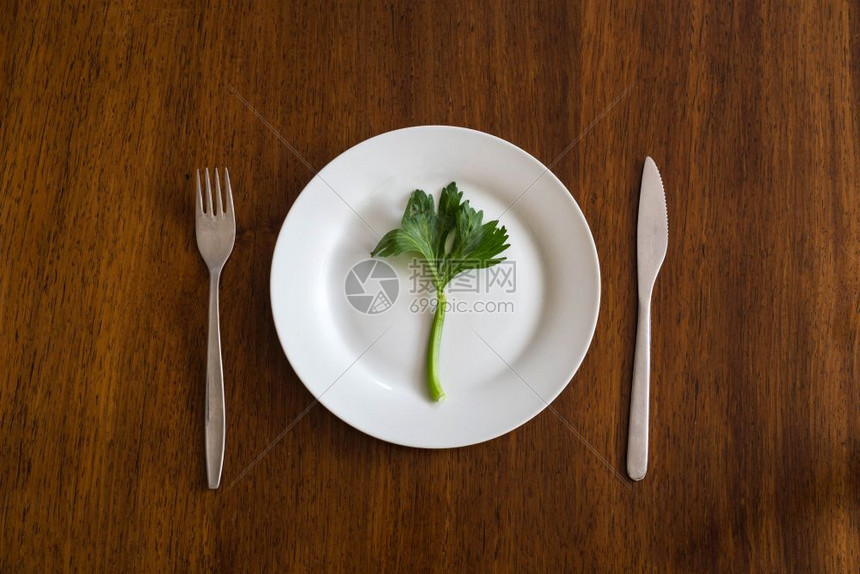 桌子空白板上的绿蔬菜在木板上煮吃健康最高视力食物的概念在空白板上吃绿色蔬菜在木板上用女手切菜身体健康白色的餐具图片