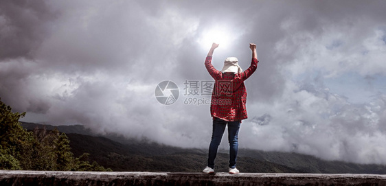 夏天女在山峰高上举起拳头天空背景成就和胜利概念以成功地站立积极的女士图片