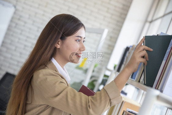 年轻女性在图书馆书架上取阅书籍图片