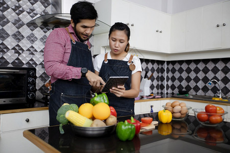 白种人浪漫的高级快乐和微笑年轻夫妇在家中厨房做饭的食物图片