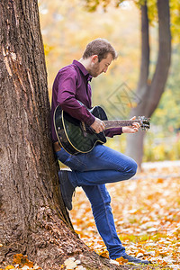 长椅成人年轻在城市公园弹音响吉他专心手持艺术家图片