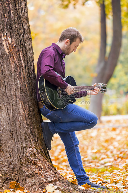 长椅成人年轻在城市公园弹音响吉他专心手持艺术家图片