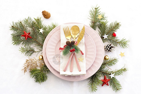 圣诞桌概念设置两个粉板和金餐具在纸巾锥形球和星上装饰粉色的刀早餐图片