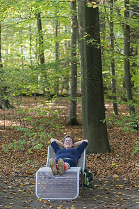 金属女人在秋天的森林里放松躺在椅子上流动的垂直图片