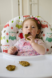 餐椅上吃东西的小女孩图片