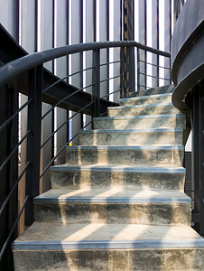 出口混凝土螺旋楼梯有金属护栏直到顶楼现代风格清晨亮光穿过铁格栅架前视和复制空间在上层的铁栏杆铺设水泥螺旋阶梯垂直的当代图片