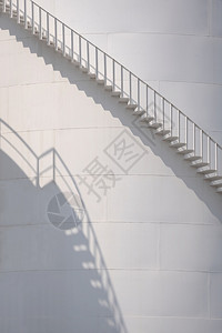 栏杆低的炼油厂垂直框架白色储油罐垂直架子的曲线楼梯表面阳光和阴影图片