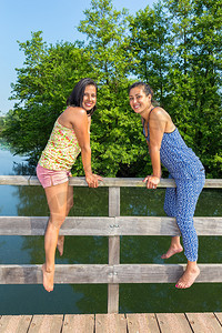 女士爱春天两名青年妇女坐在一起水上的桥图片