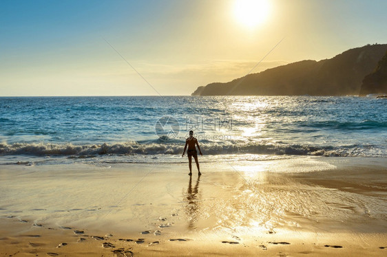 男子站在海滩上看日落图片