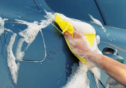 用肥皂泡沫中的黄色抹布清洗灰汽车女人的手擦拭汽车侧面用肥皂泡沫中的黄色抹布清洗灰汽车污垢运输洗涤图片
