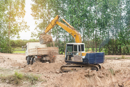 黄色挖掘机将土壤装入建筑工地的倾卸卡车中力量液压进入图片