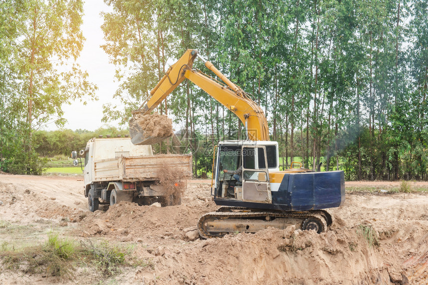 黄色挖掘机将土壤装入建筑工地的倾卸卡车中力量液压进入图片