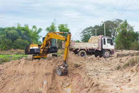 伊拉克重的进入黄色挖掘机将土壤装入建筑工地的倾卸卡车中图片