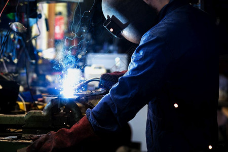 闪光焊工在车库里接工厂的业人在焊接钢结构工作焊在车库里接工厂的业人在焊接钢结构金属男人图片