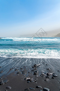 海滨黑沙滩与岩石海浪图片