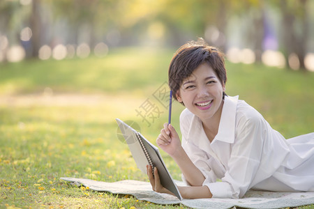 作家亚洲人草地夏月公园有书笔的亚裔年轻女放松时光的快乐情绪图片