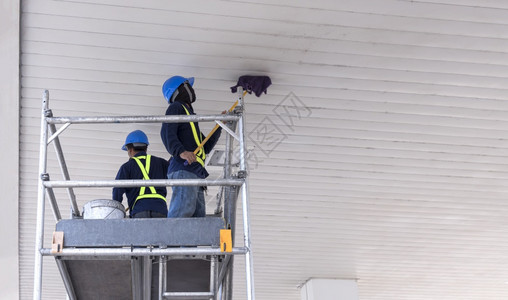 高的2名工人在金属脚手架上低角度视他们用拖棍清洗加油站的白色天顶屋拖地男人图片