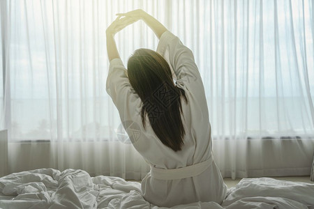 漂亮的早上在豪华酒店的床上醒来时身穿浴衣的亚裔妇女背面生活方式和假日概念平衡女孩图片