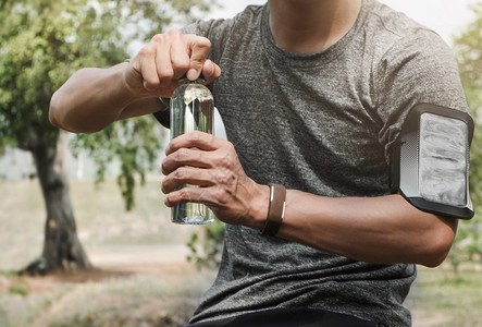 男人运动的疲累体育运动员开一瓶有自然背景的水瓶公园图片