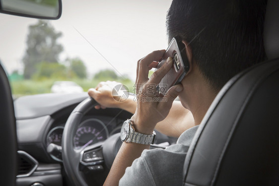 男子驾驶汽车时使用手机说话的人男驾驶汽车镜子里面沟通图片