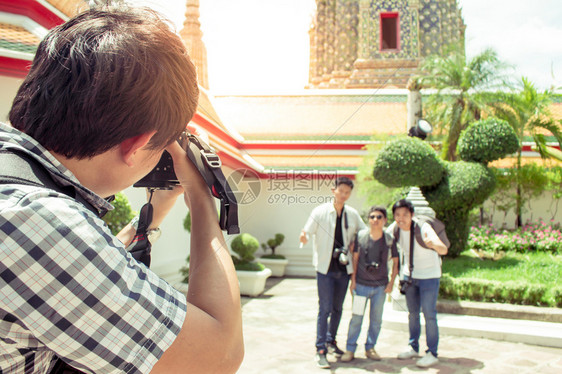 亚洲黑色的涉水男游客在泰国寺庙里拿着相机拍照并朋友片图片