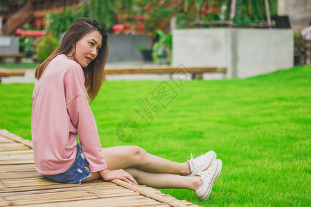 夏天年轻的女士坐在竹桥上身穿粉红衬衫的女人图片
