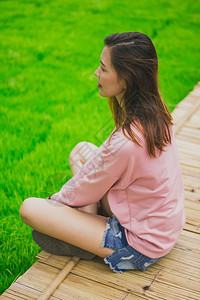 成人场地假期坐在竹桥上身穿粉红衬衫的女人图片