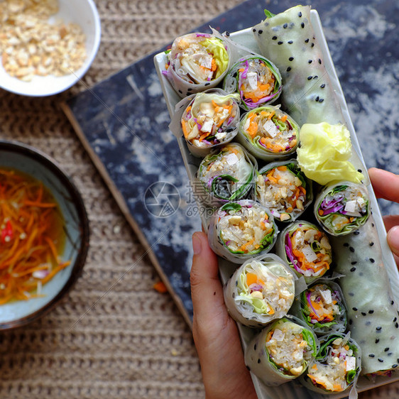 酱越南春卷素材背景的切片食大米纸卷丰富多彩的蔬菜制作了健康美味的素食菜盘子女士轧制图片