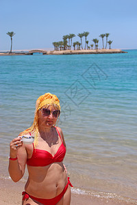 天有魅力的女孩在海滩上享受放松喝咖啡拿着杯在海滩上放松的女人漂亮在海边放松比基尼吸引人的图片