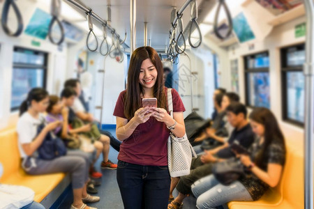 使用Skytrain铁路或地的智能移动电话在大城市旅行生活方式和交通概念中搭乘便衣亚洲女客在大城市旅行生活方式和运输概念车站日本图片