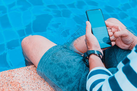 男联系聪明的在游泳池使用手机的现代人图片