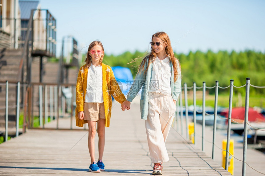 步行夏季在港口码头的可爱小女孩一起在船上行走其背景为在港口的可爱小女孩夏天在港口的可爱小女孩积极的白种人图片