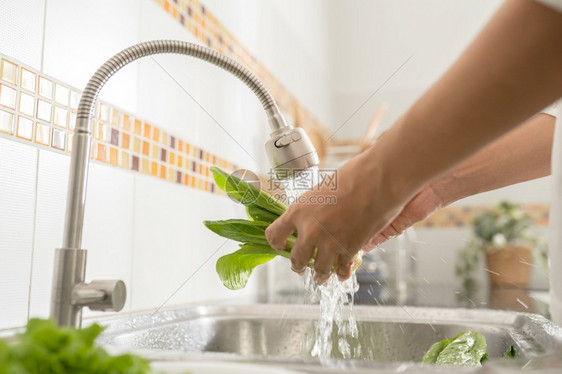 亚洲妇女在厨房里洗蔬菜在家中做早饭时准备食物生菜近手拉亚洲妇女在厨房里清洗蔬菜生的为了身体图片