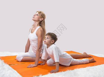 一个美丽的年轻母亲和儿子一起做瑜伽在室内女孩姿势图片