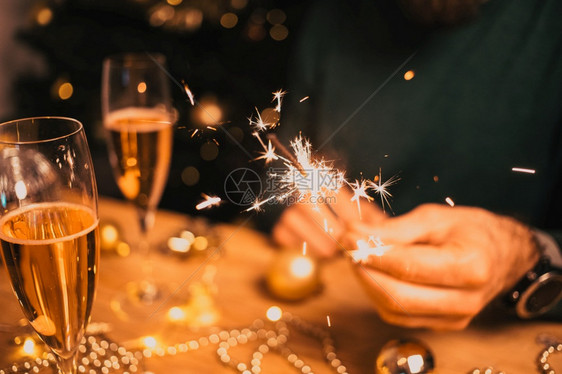 女士圣诞节男人拿着火花和香槟杯新年晚会图片