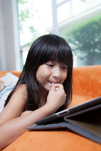 思考女孩在家里的橙色沙发上玩石板乐趣通讯图片