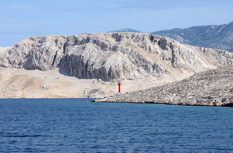 标记岩石海有山地背景的岛上红光照亮图片