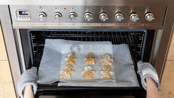 在烤箱里姜饼人在箱里做自制姜饼人干的女特写在烤箱里姜饼人在箱里做自制姜饼人干的女纸制造假期图片