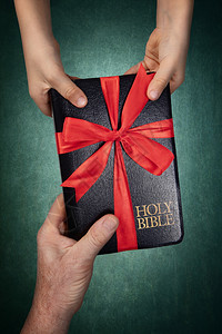 下一个人之手把圣经作为礼物赠送给孩子用红丝带捆绑宗教书图片