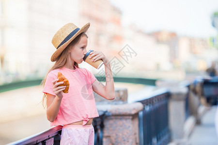 美丽的小旅游女孩有羊角面包和户外咖啡在河边的女郎前列车厢上有牛角面包和咖啡在车门外一种生活景观图片