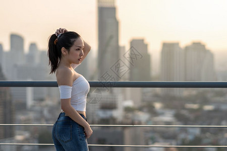 城市头发街道身穿感时装衣的亚洲勇女人肖像站在城景背的屋顶上美丽体形概念的身材图片