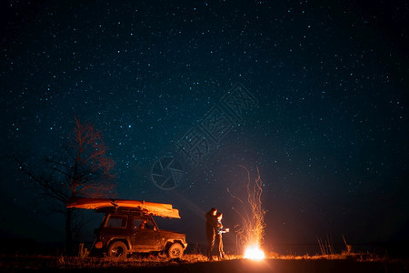 欢乐的情侣女站在星空前燃起的营火中享受着宁静的夜晚图片