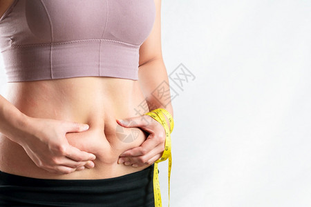 重量胖女人肚子乎的肥女人手握着过多的腹部脂肪用卷尺女人的饮食生活方式概念女孩脂肪团图片