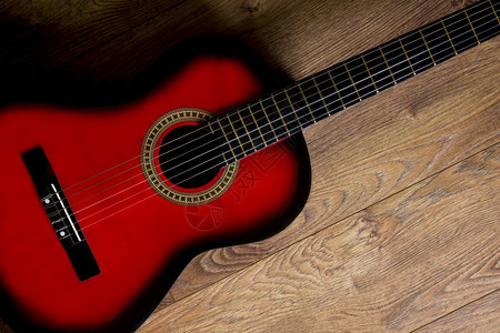 木头抽象的红黑色古典吉他站在木地板上内部的图片