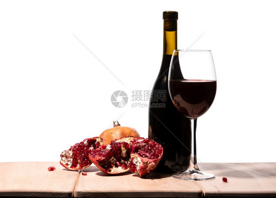 软木白本上孤立的布甘底红酒瓶葡萄杯和多汁的石榴空食物图片