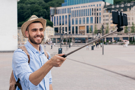 电话女美国人带着背包智能手机自拍的快乐青年男子肖像图片
